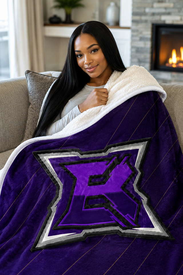 Woman wrapped in the BlanK Huge B sherpa blanket, purple printed face with the cream sherpa reverse folded back