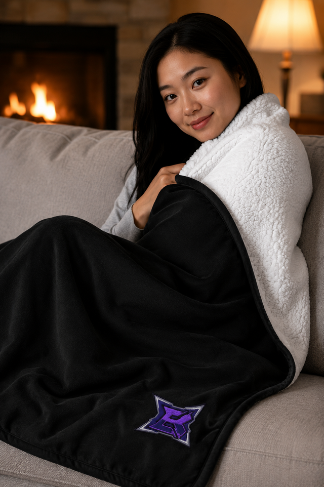 Woman wrapped in the Premium Sherpa Blanket with the embroidered BlanK B, showing the plush white sherpa reverse